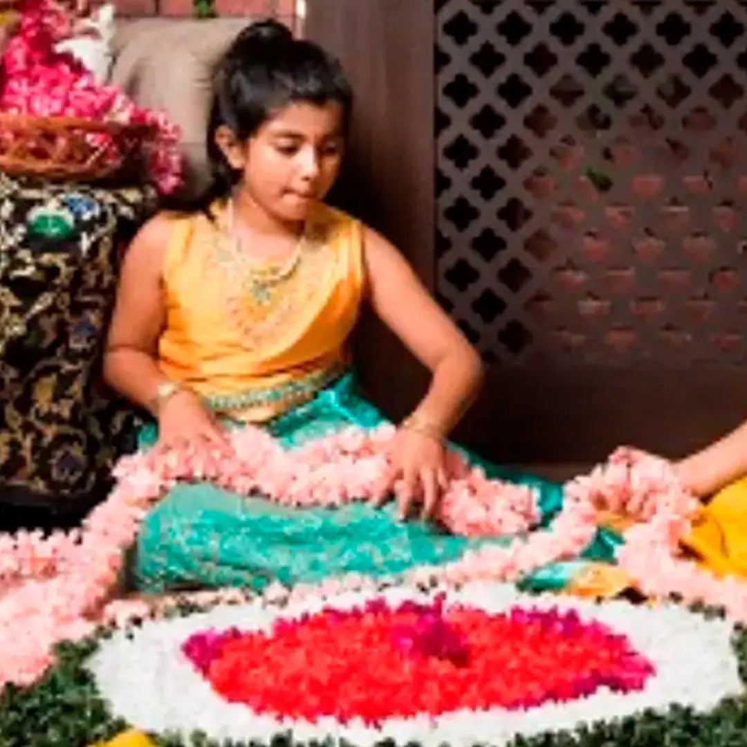 A young girl in traditional Indian attire creating a vibrant flower arrangement together.