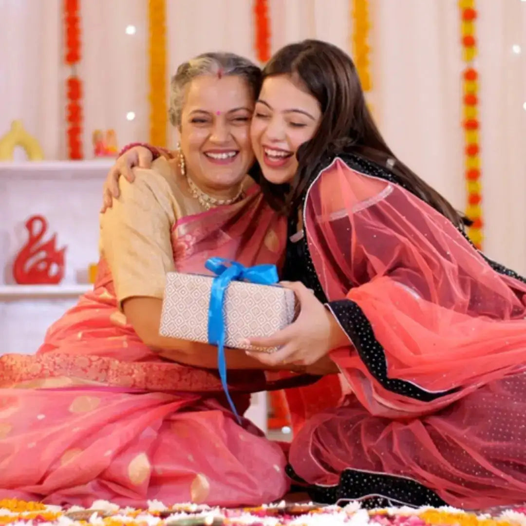 Two people embracing with a gift box during a South Indian saree function at a half saree ceremony