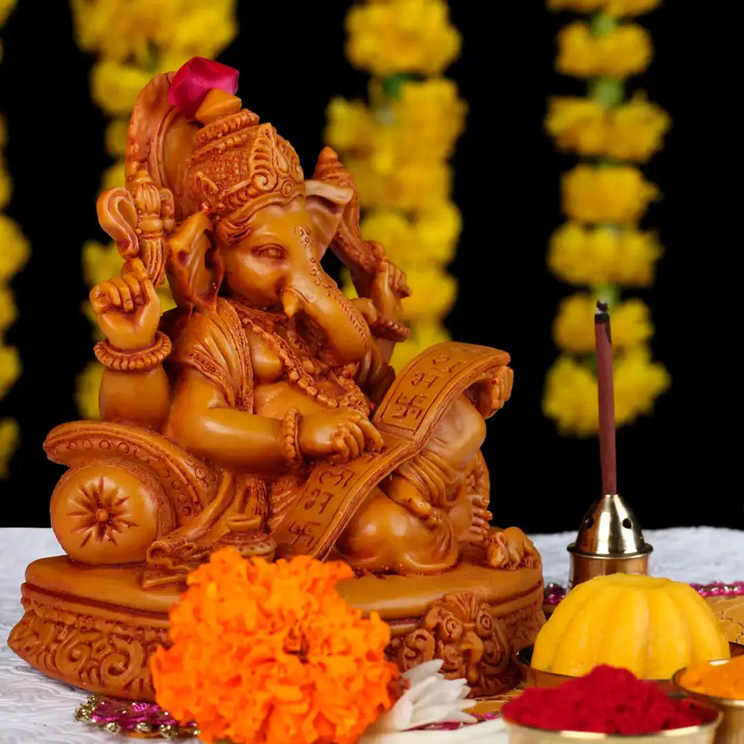 A statue of Ganesh seated on a table, surrounded by vibrant flowers, symbolizing prosperity and wisdom.