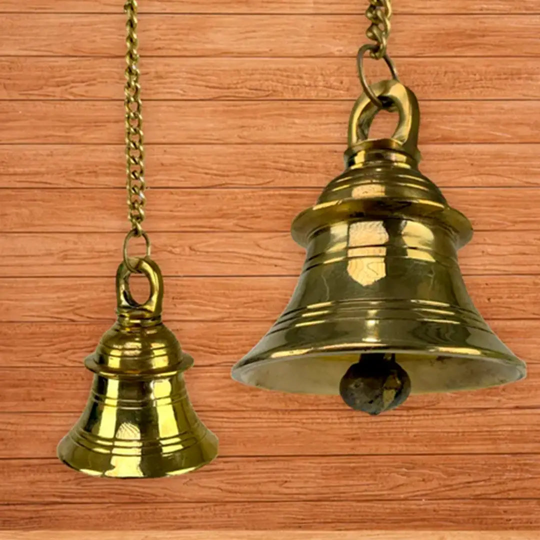 Two brass bells suspended from a rustic wooden wall, showcasing a blend of elegance and craftsmanship.