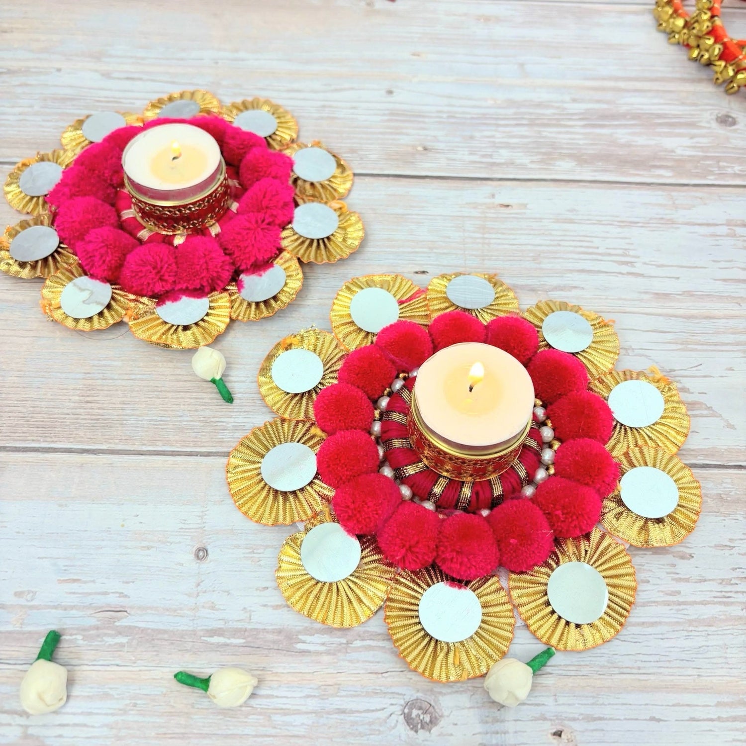 Ornate circular candle holders with pink pom-poms, gold ruffles, and mirrors for festive decor