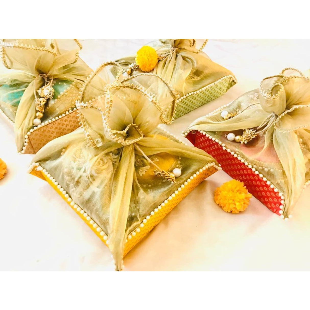 Golden fabric pouch with yellow pom-poms and pearl accents from a luxury brand