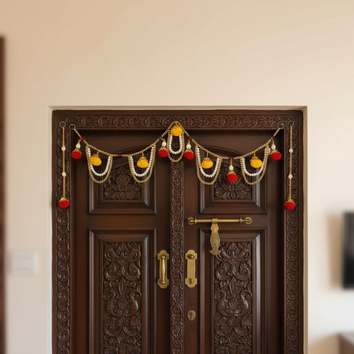 Decorative Indian Door Toran with red and yellow pom-poms and pearl accents for festive decor
