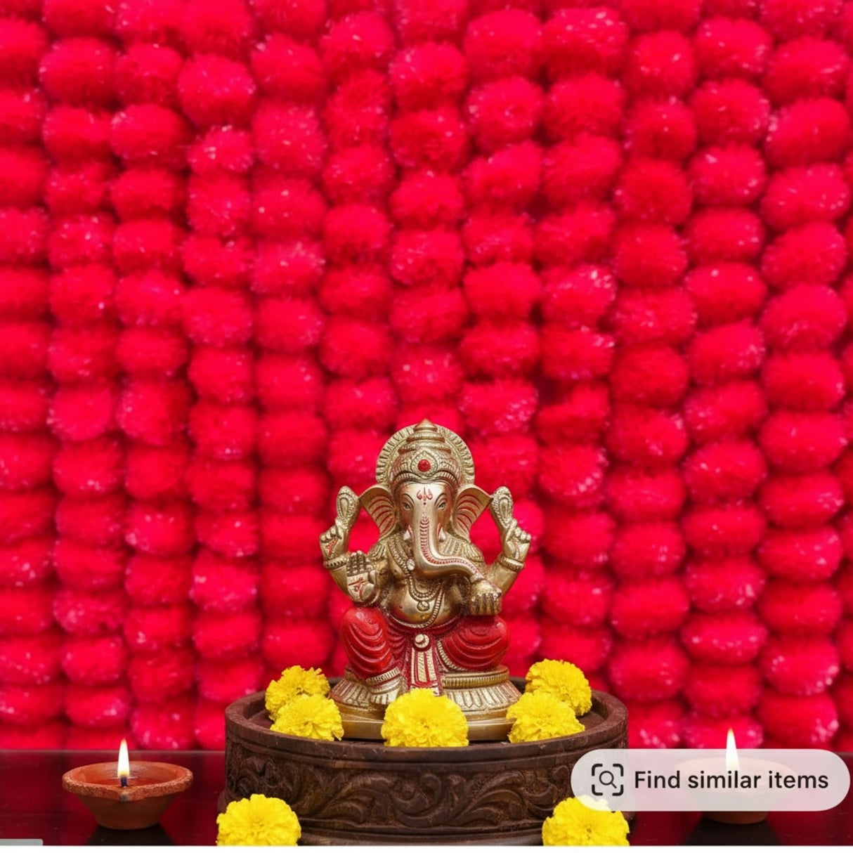 Golden Ganesha idol with red and yellow accents surrounded by yellow marigolds