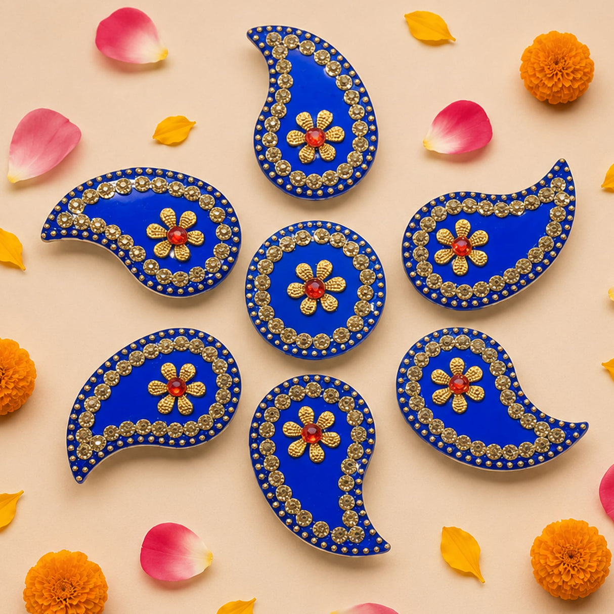 Acrylic rangoli set with vibrant blue paisley shapes adorned with gold embellishments and red gemstone centers