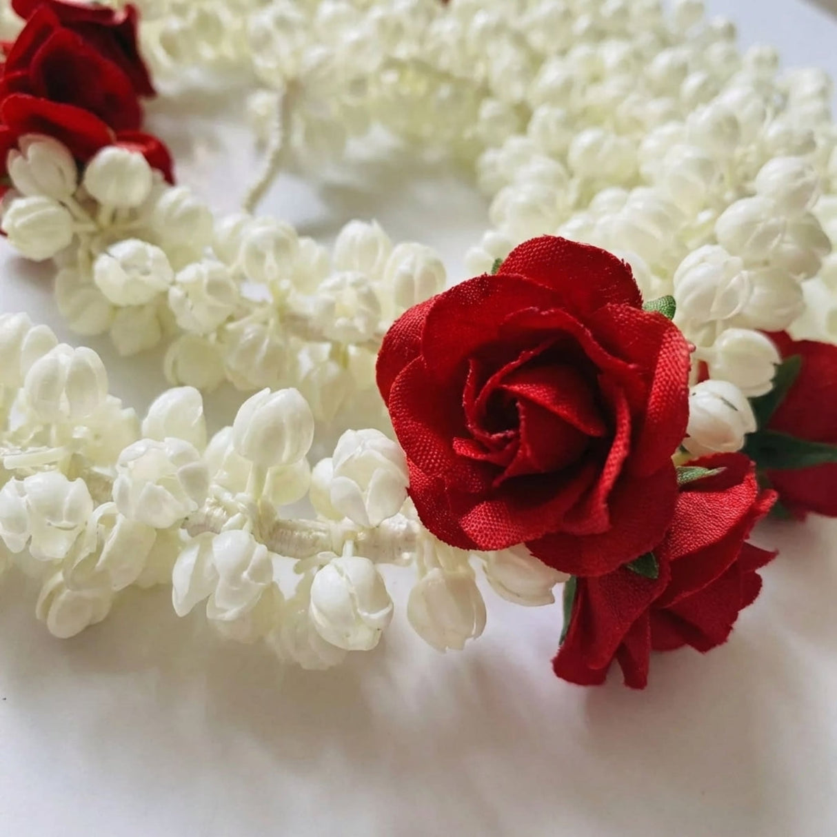 Artificial jasmine buds and rose garland featuring white jasmine blossoms and red silk roses for traditional indian decor