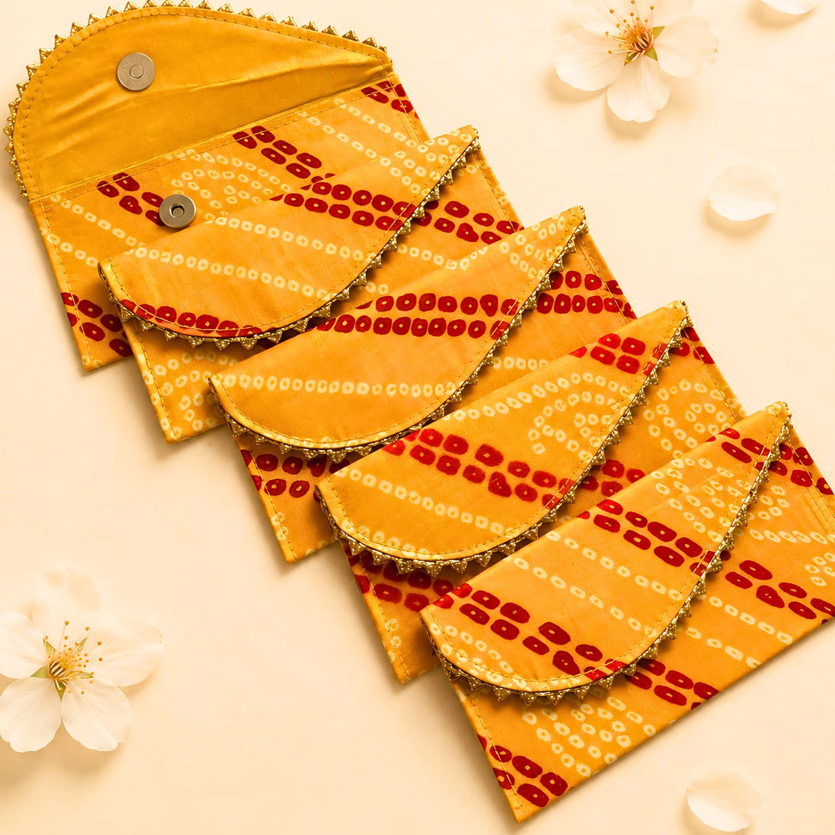 Vibrant yellow and red brocade fabric money envelopes with gold-trimmed edges and decorative bandhani pattern for gifts