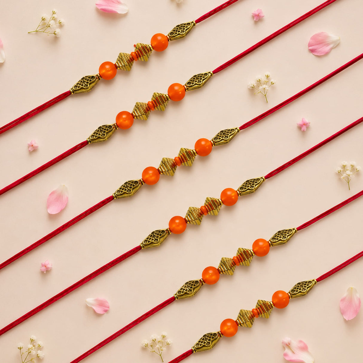 Designer bead rakhi with red cord orange beads and gold-toned leaf-shaped charms for brother and bhabhi gift