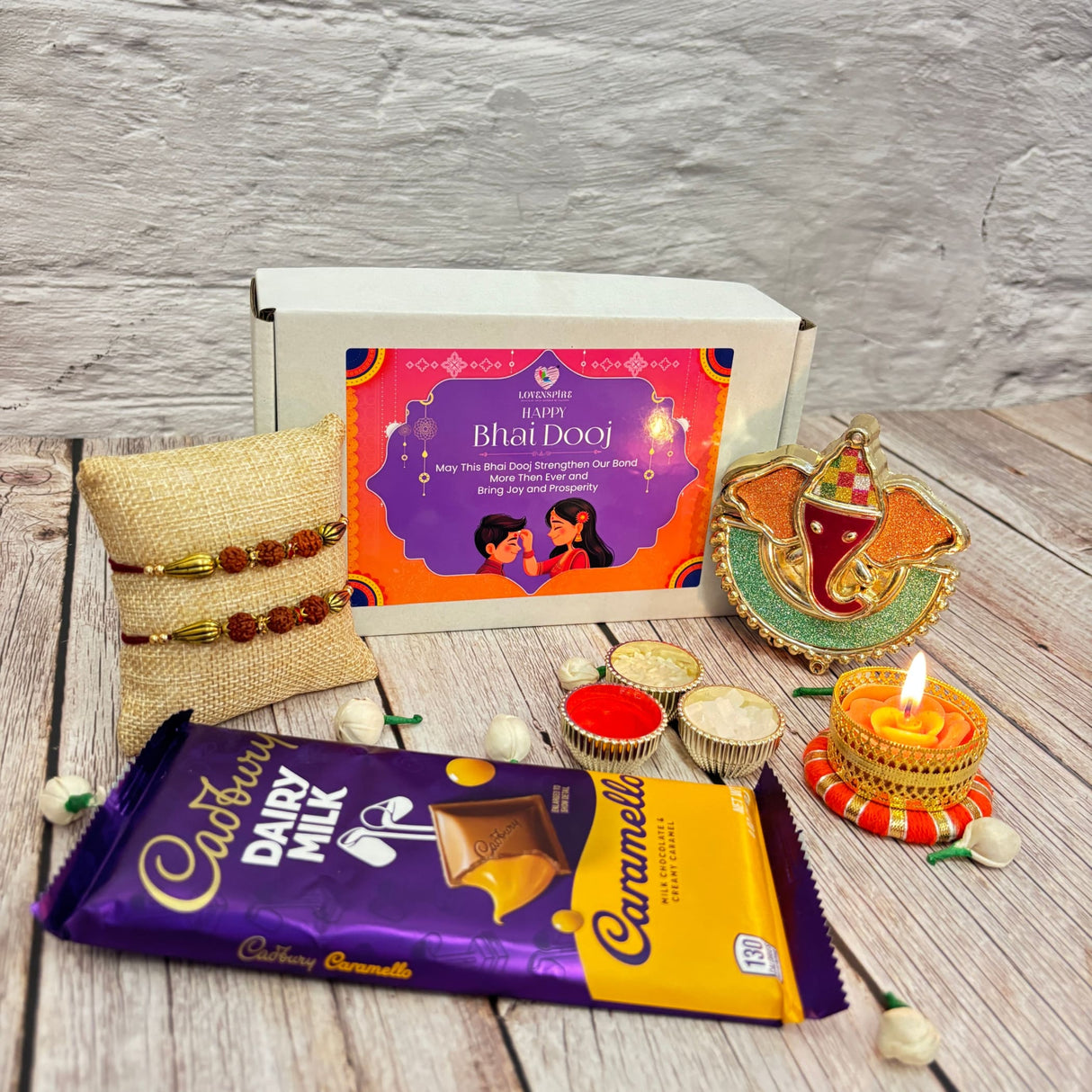 Bhai Dooj gift set with chocolates, rakhis, Ganesha idol, and decorative candle