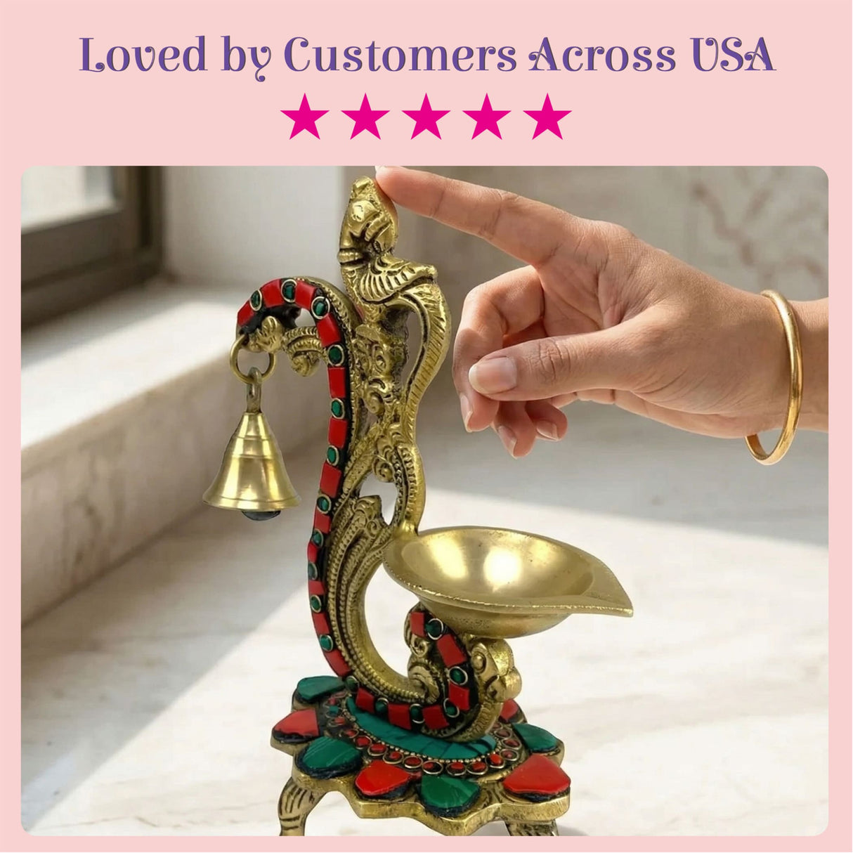 Golden brass oil lamp diya with intricate red and green mythical creature design and small hanging bell for diwali decor