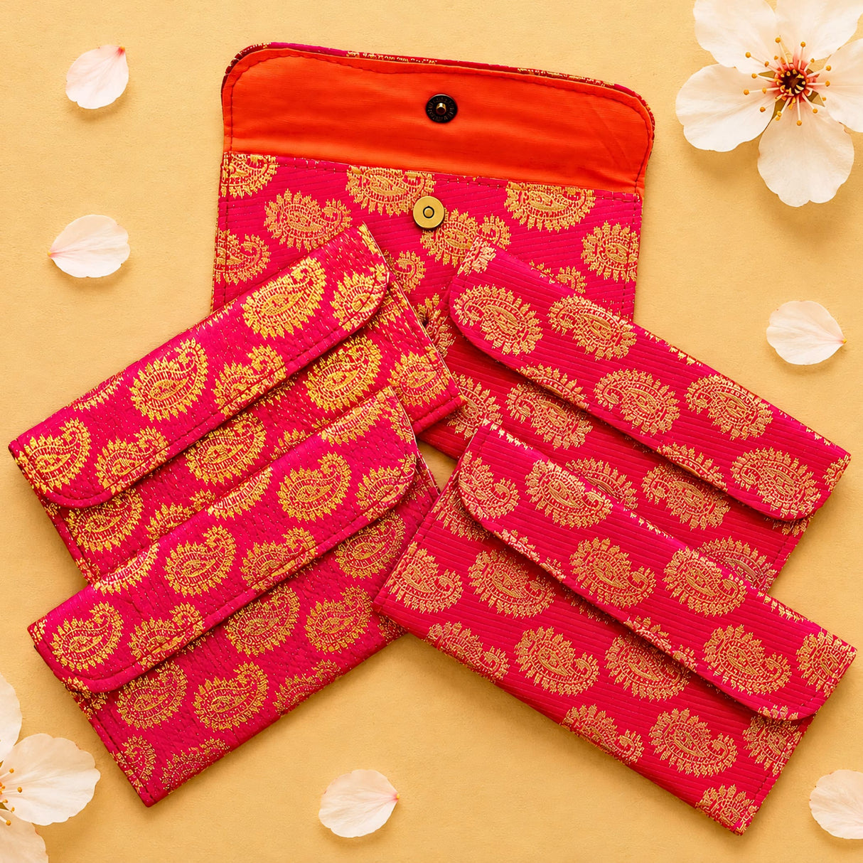 Vibrant pink and gold brocade fabric paisley quilted clutch with orange interior and black button closure for Indian weddings