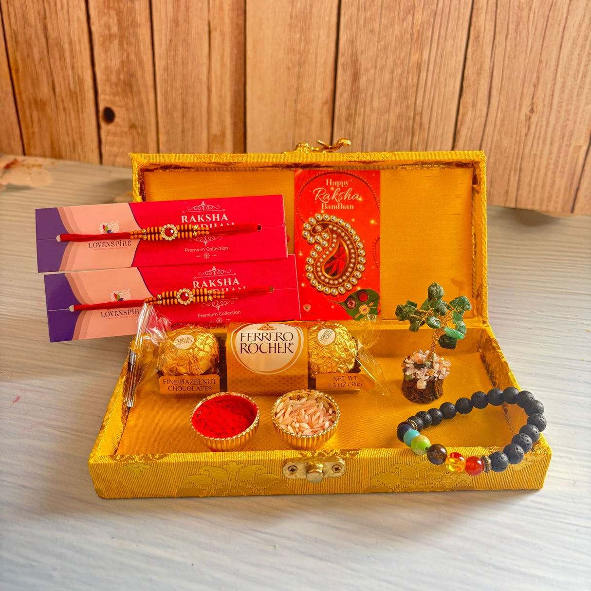 Golden ornate designer rakhi gift hamper with red and gold rakhis chocolates crystal tree and traditional offerings