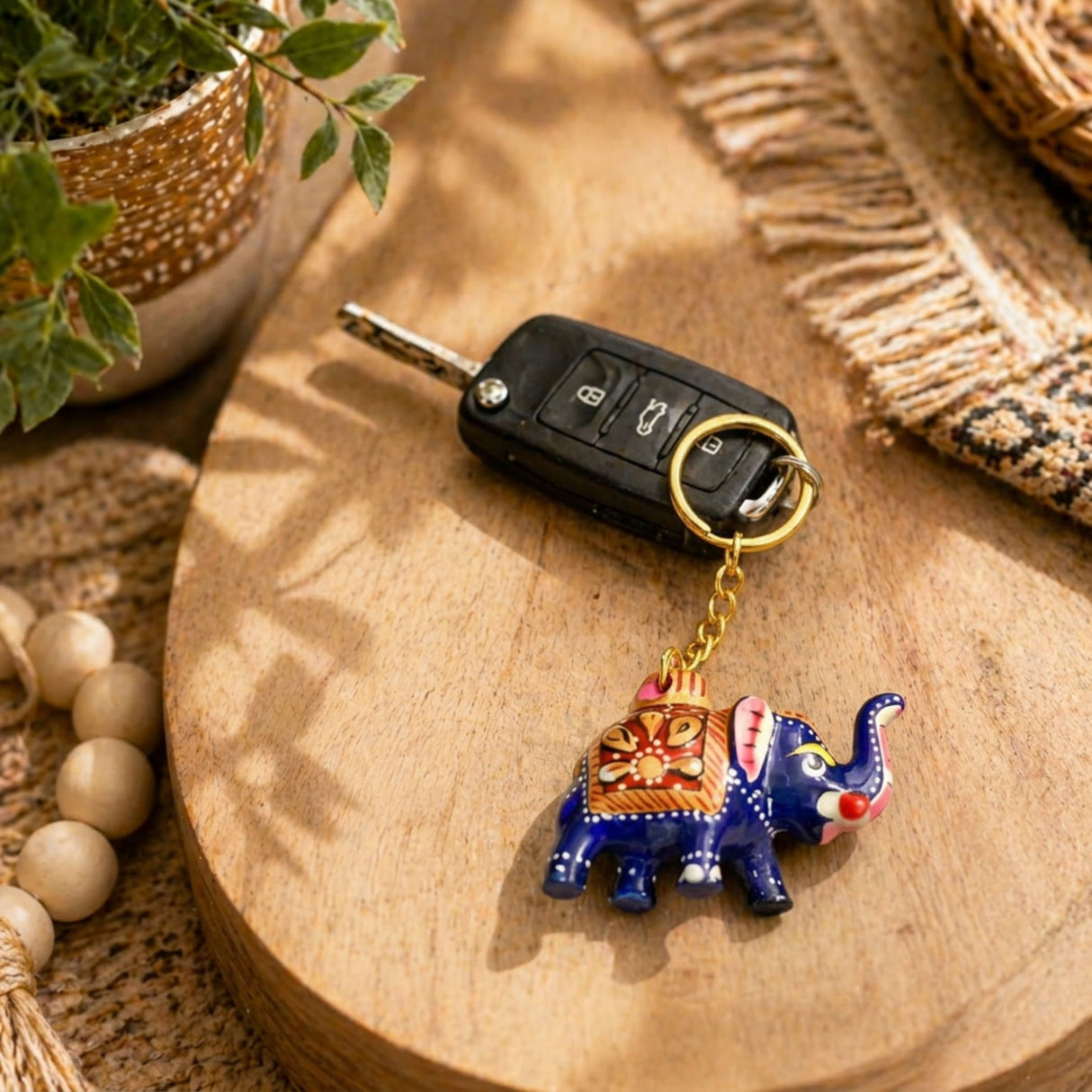 A vibrant blue handmade ceramic elephant keychain with orange gold and pink patterns ideal for good luck charm gifts