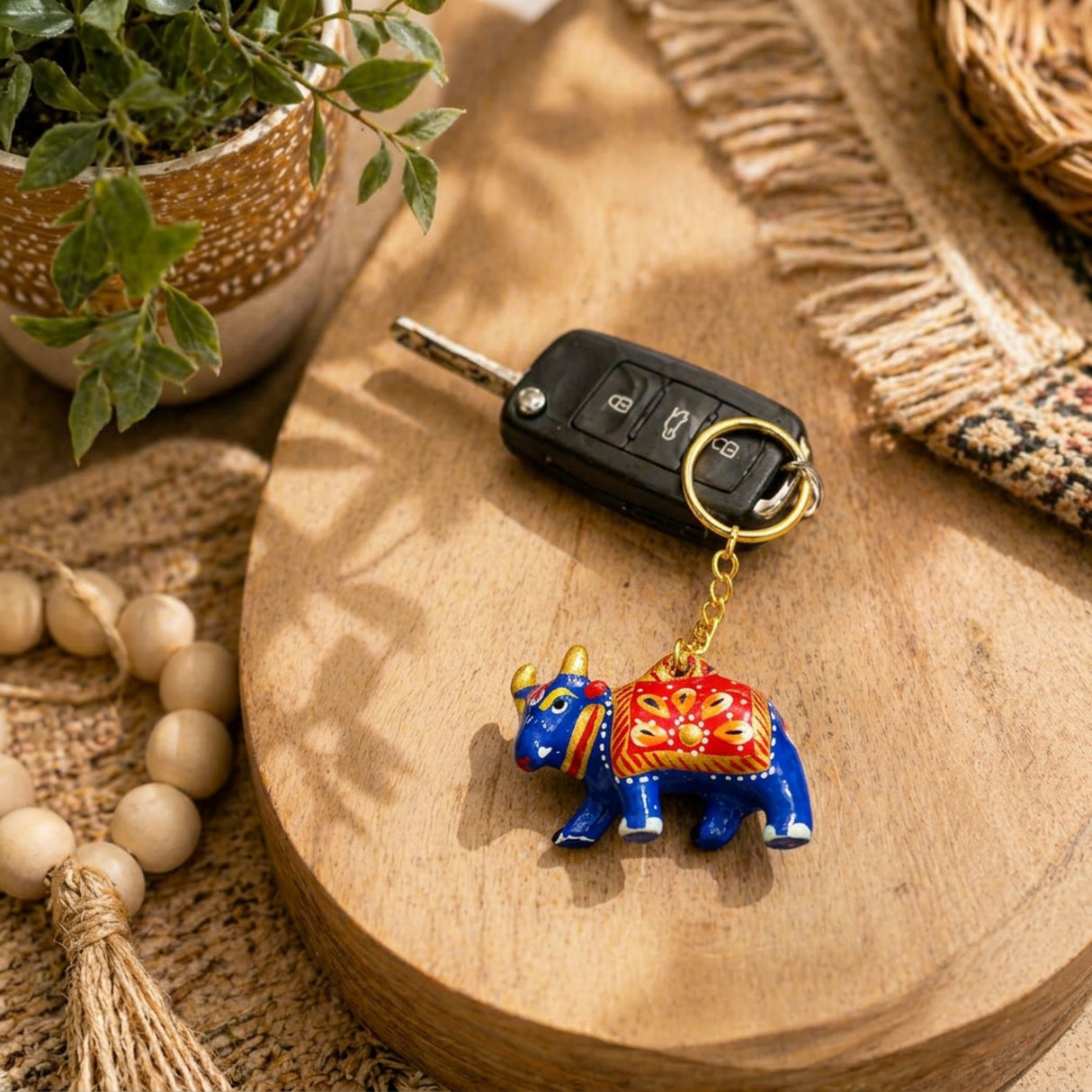 Handmade ceramic blue elephant keychain with red gold patterns and golden horns attached to a car key ring