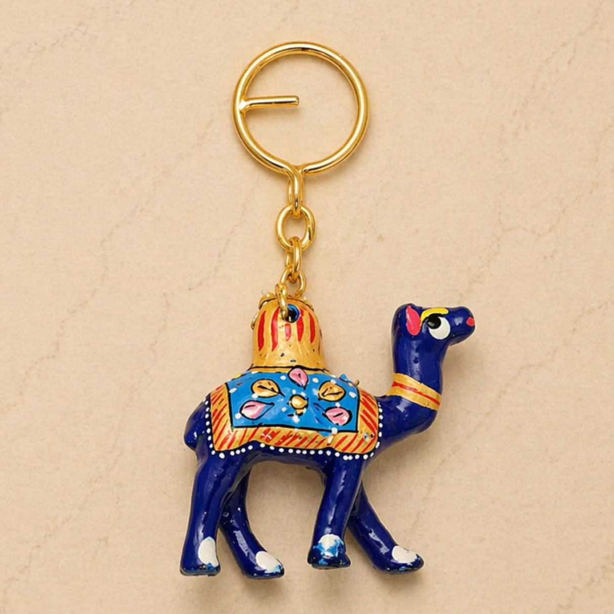 A vibrant blue handmade ceramic camel keychain with gold pink and orange patterns, ideal indian good luck charm
