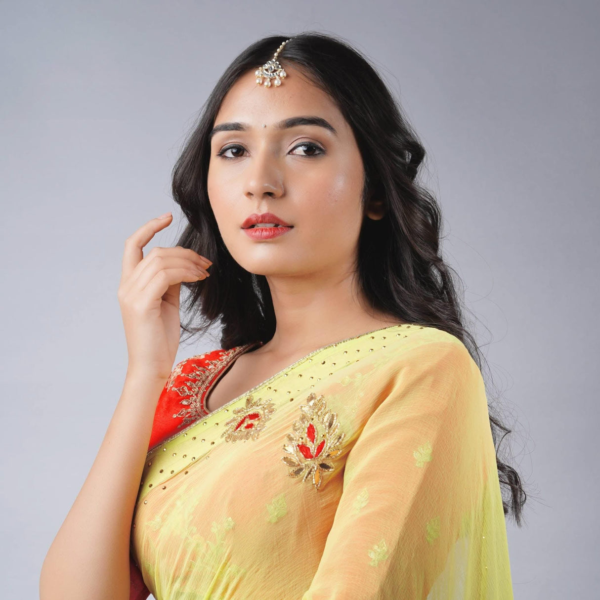 Woman in vibrant yellow saree with Chand Tikka gold-plated maang tikka