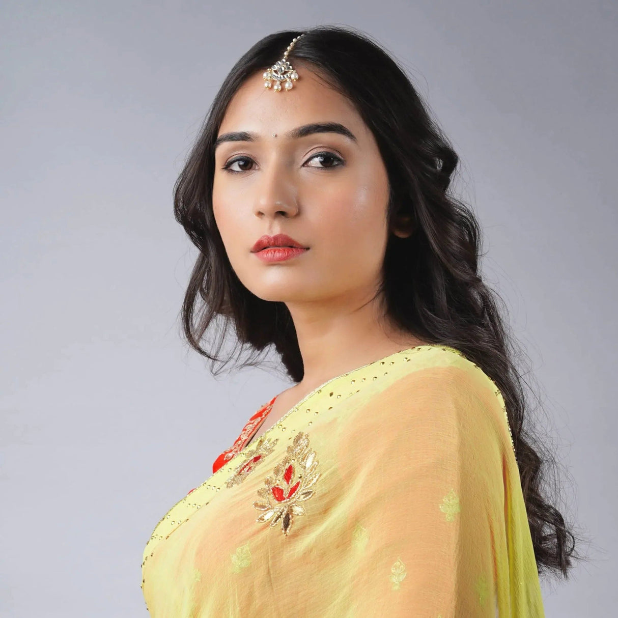 Delicate gold red floral embroidery on light yellow saree shoulder with Chand Tikka