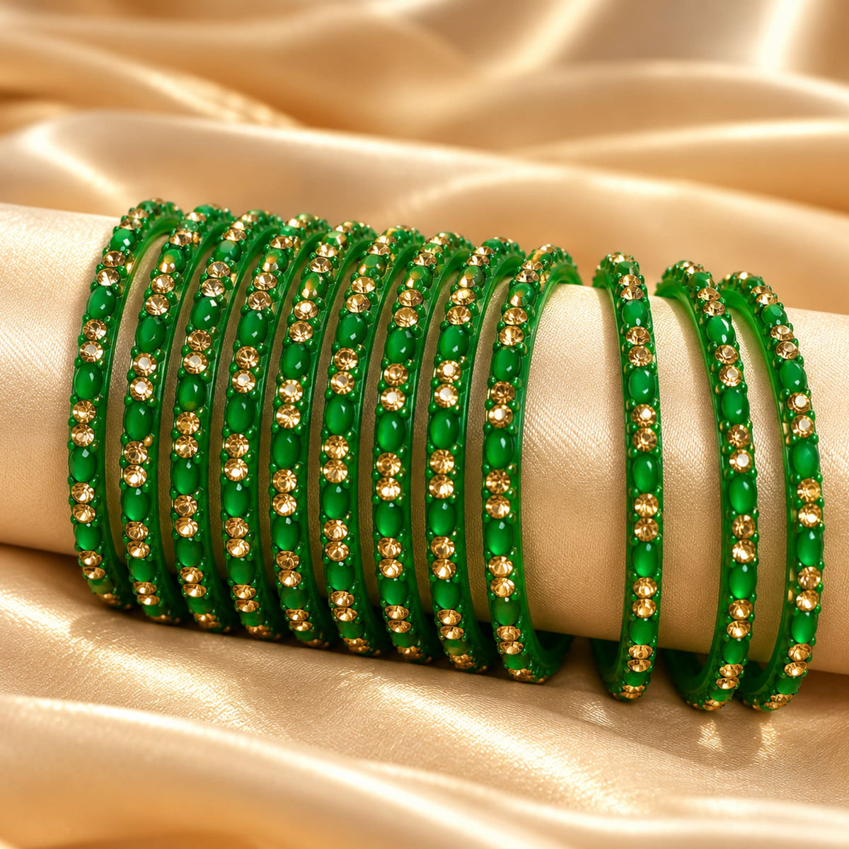 A set of vibrant green 12ct glass bangles adorned with sparkling gold toned stones on a cream display for bridal gifting