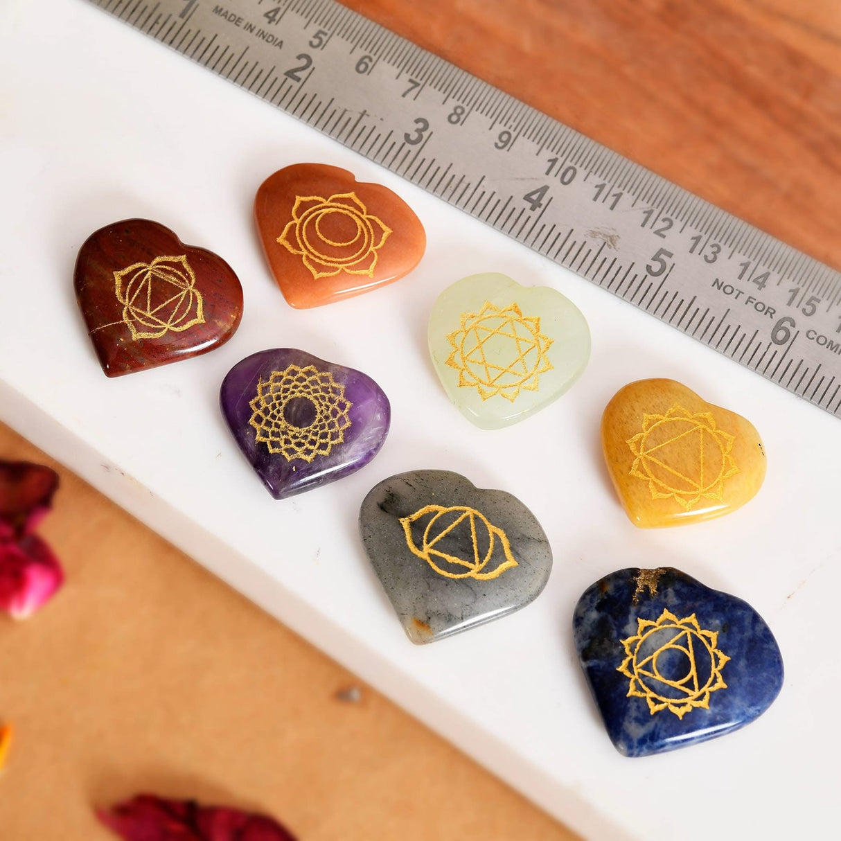 Seven heart-shaped chakra stones with golden engraved symbols for meditation and healing