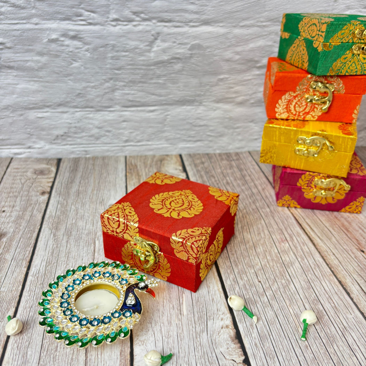 Colorful ornate gift boxes and a peacock-shaped tealight holder for Diwali celebration