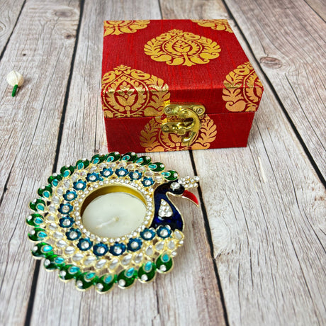 Red decorative box with gold latch and peacock-shaped candle holder for Diwali gift hamper