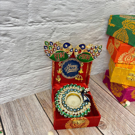 Red gift box with peacock-themed tealight holder and Happy Diwali sign for festival gifting