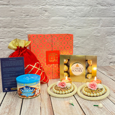 Festive Diwali gift set with almonds chocolates candles and decorative items in a red gift bag