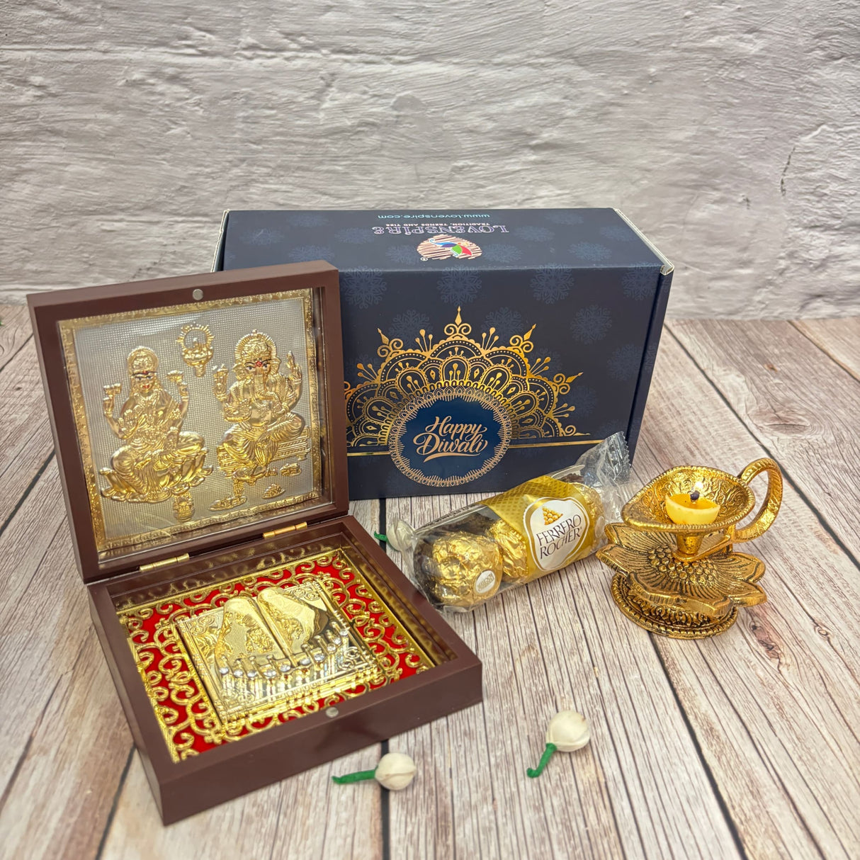 Festive Diwali gift box with religious idols, chocolates, and a diya lamp
