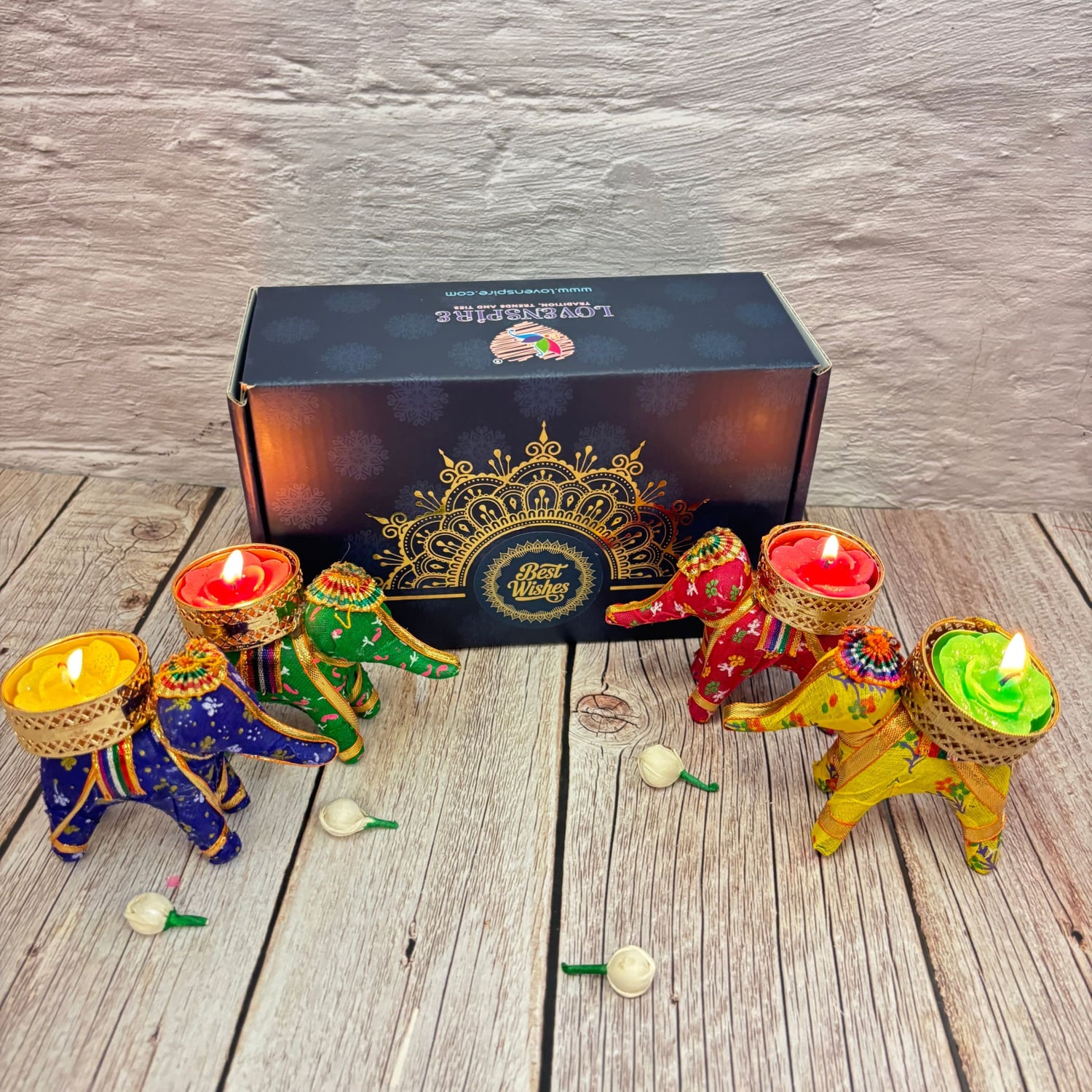 Colorful elephant-shaped tealight candle holders with lit candles and decorative gift box