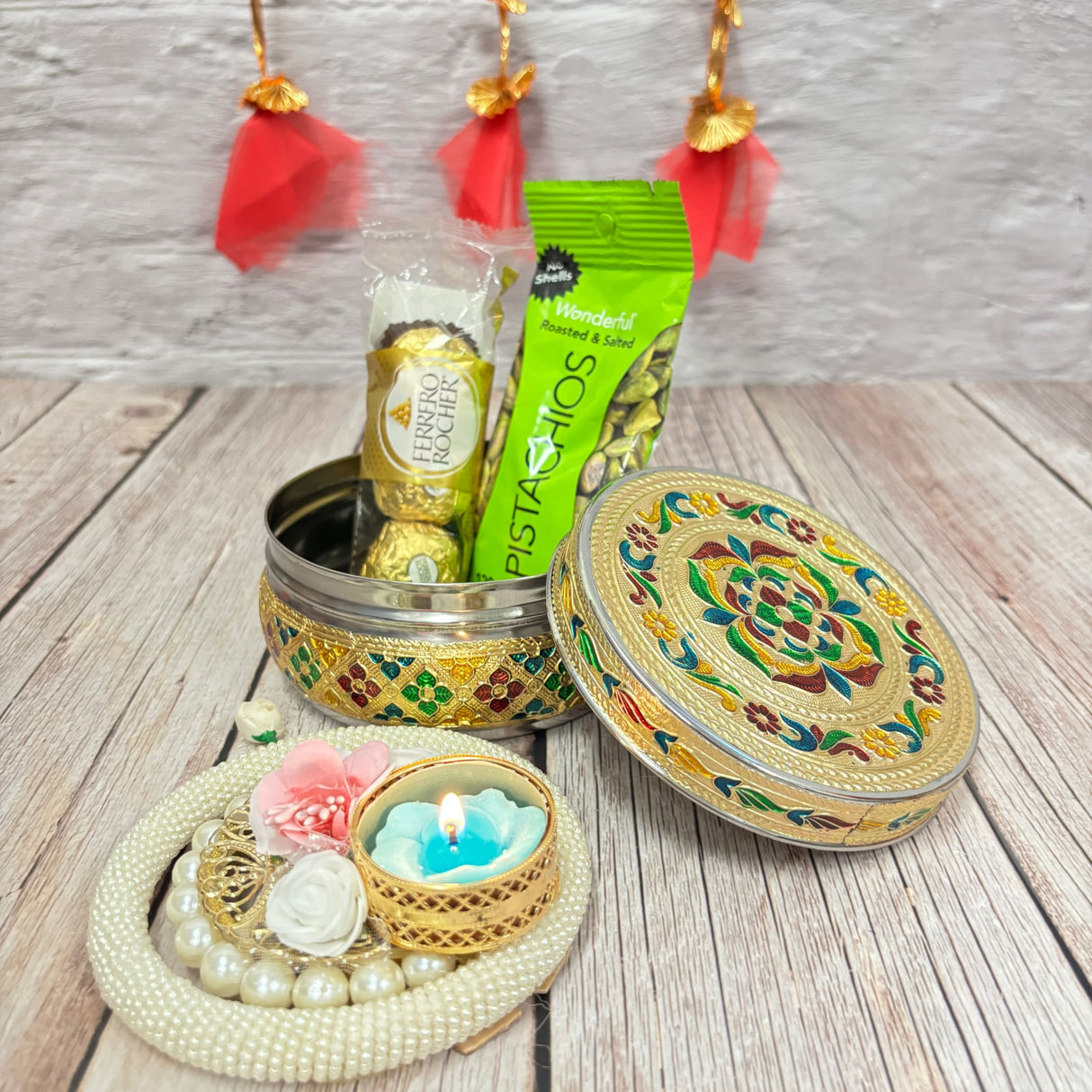 Decorative Diwali gift set with pistachios, chocolates, floral accents, and candleholder