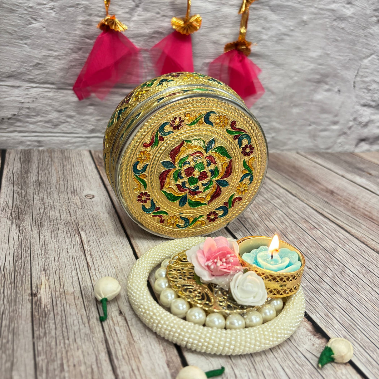 Round golden gift box with intricate colorful enamel floral patterns for Diwali celebrations