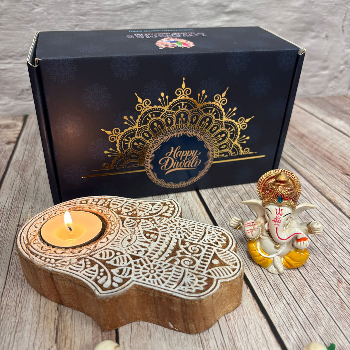 Dark blue Diwali gift box with gold mandalas, hand-shaped tea light holder, and Ganesha idol