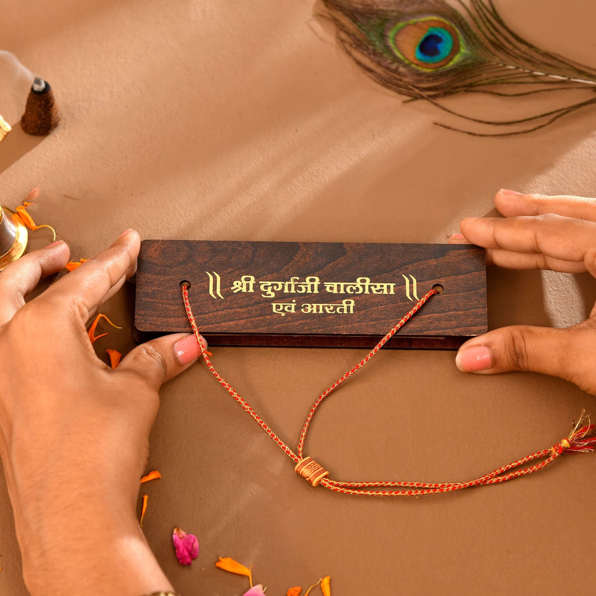 Brown wooden plaque with orange thread bracelets and silver beads for Durga Chalisa