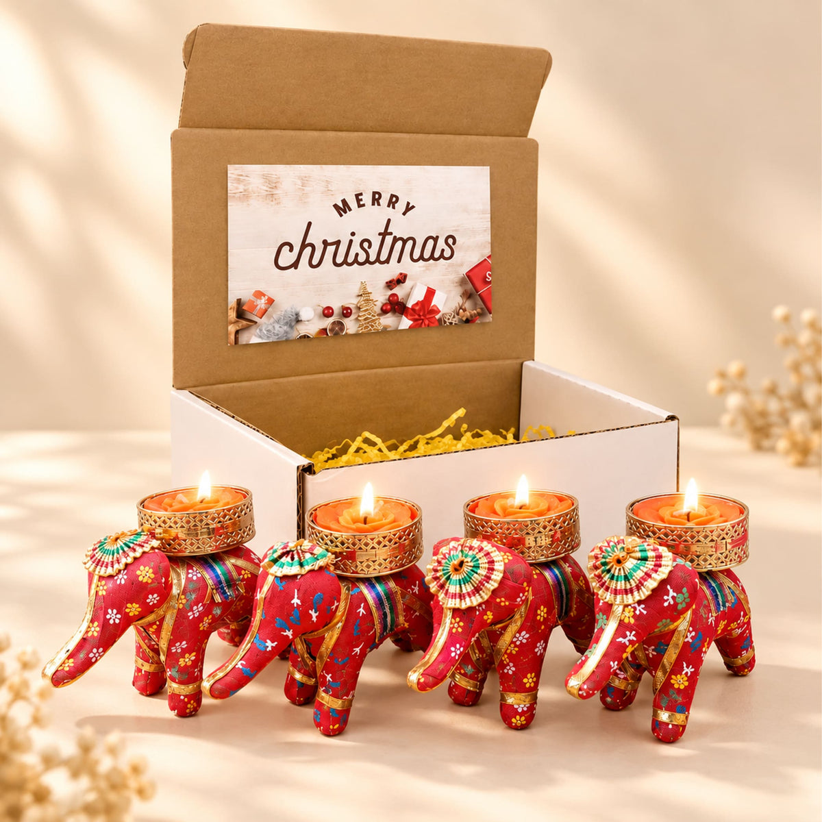 Red elephant-shaped tealight candle holders with intricate gold and colorful embroidery in a festive gift box