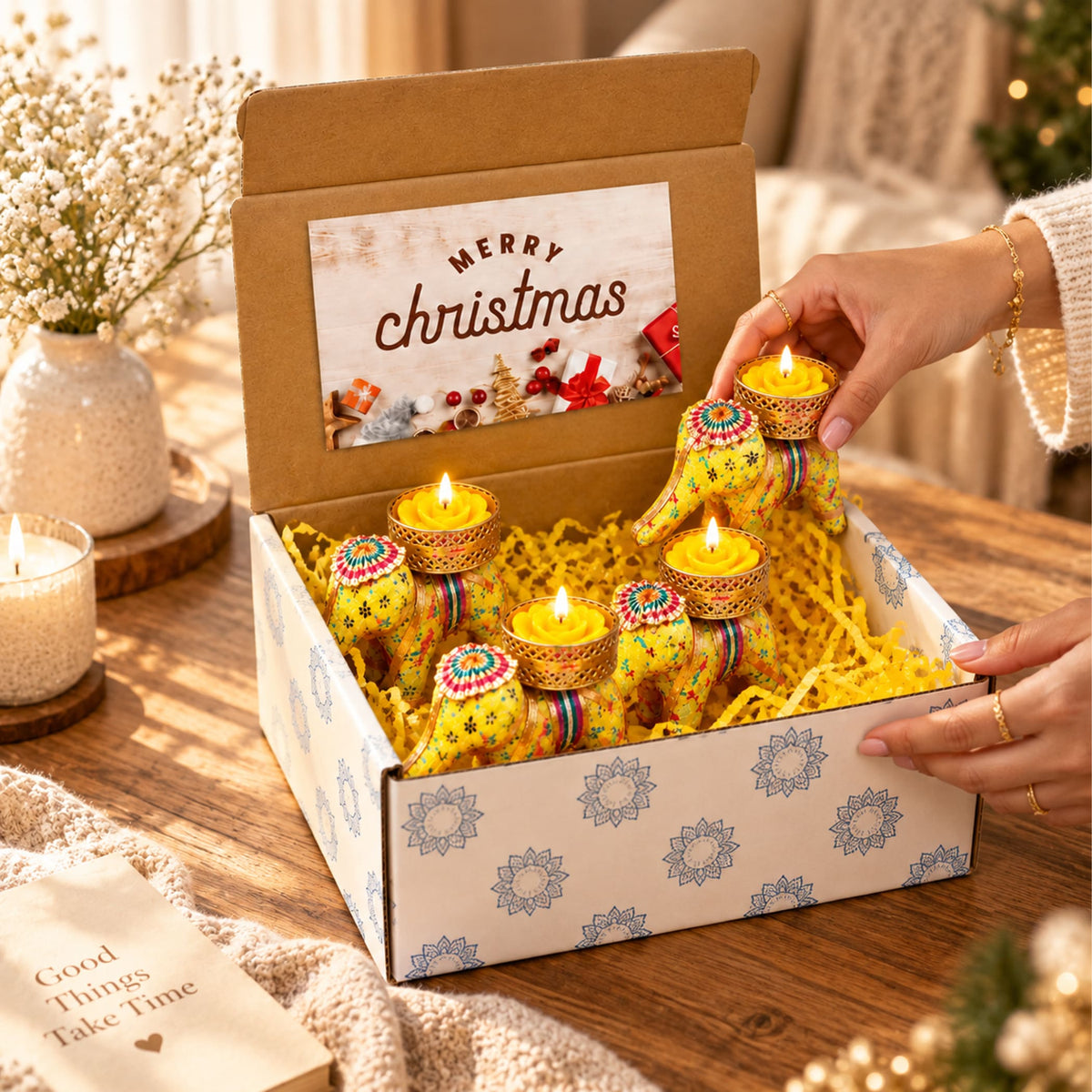 Gift box with four yellow elephant-shaped diwali oil lamps featuring intricate colorful patterns and gold-toned bases
