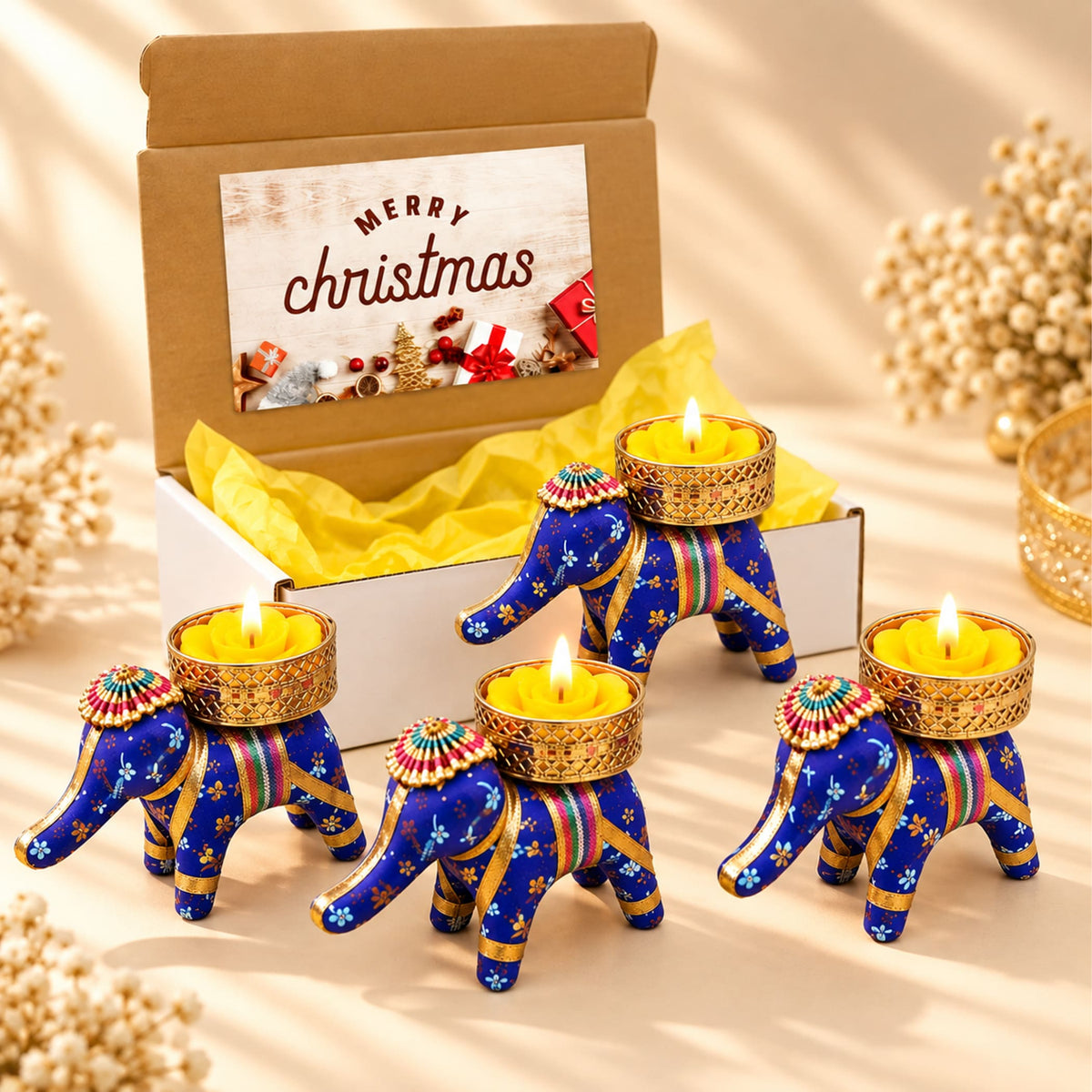 Gift box with 4 blue elephant-shaped tealight candle holders with gold accents and colorful patterns for festive gifting