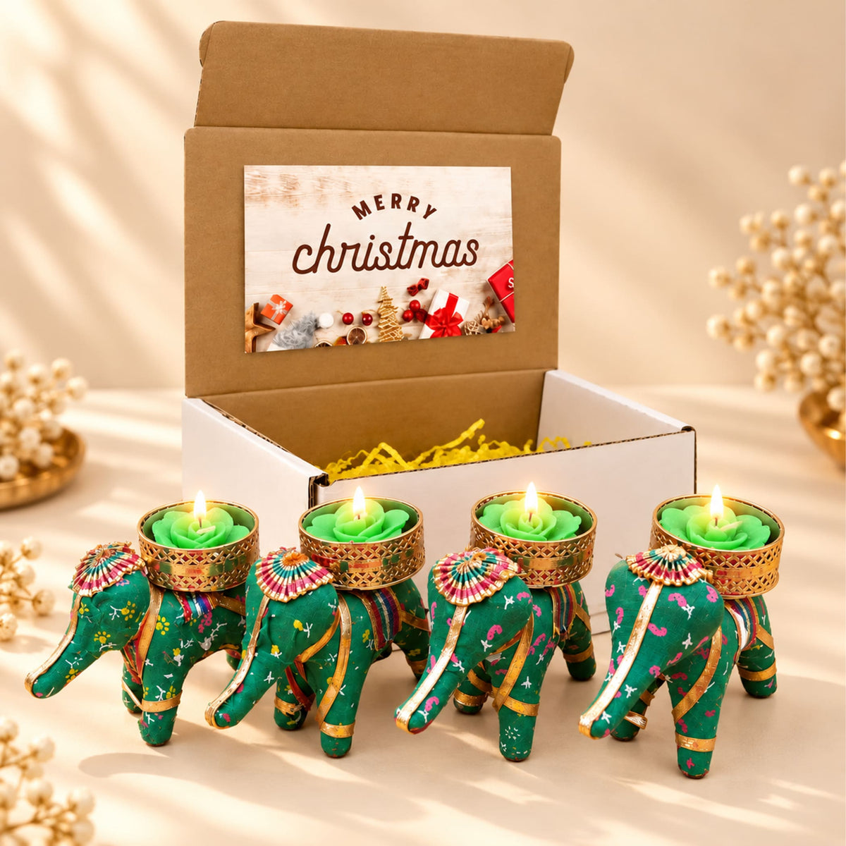 Gift box with four green elephant-shaped tealight candle holders featuring gold trim and colorful embroidery for festive gifting