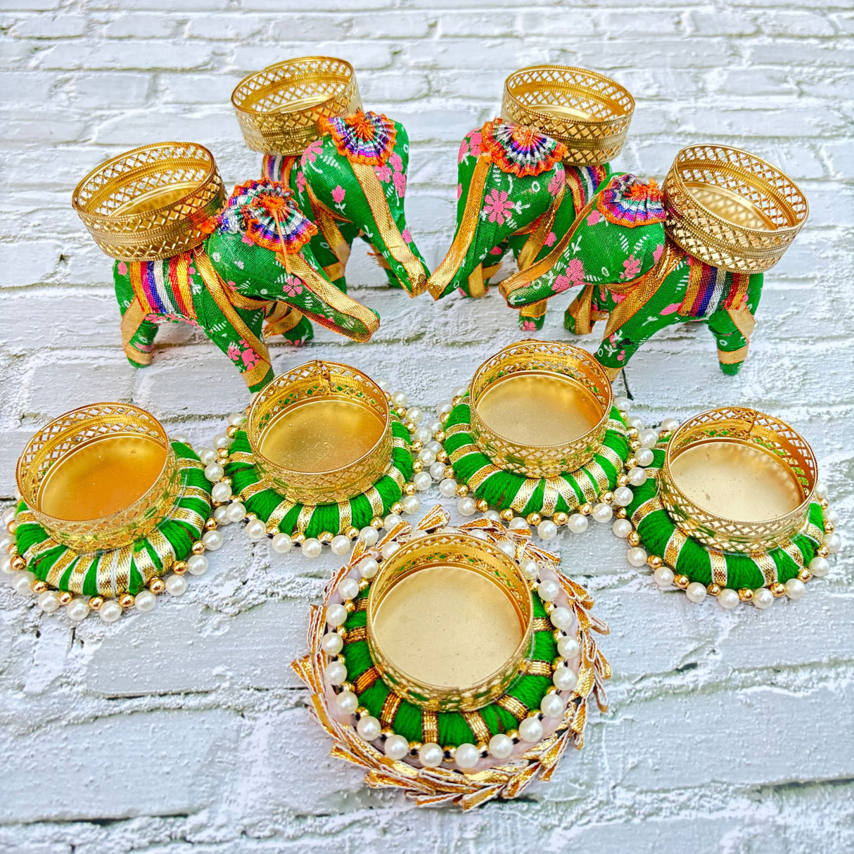 Green and gold elephant-shaped and circular candle holders with pearl accents for festive decor