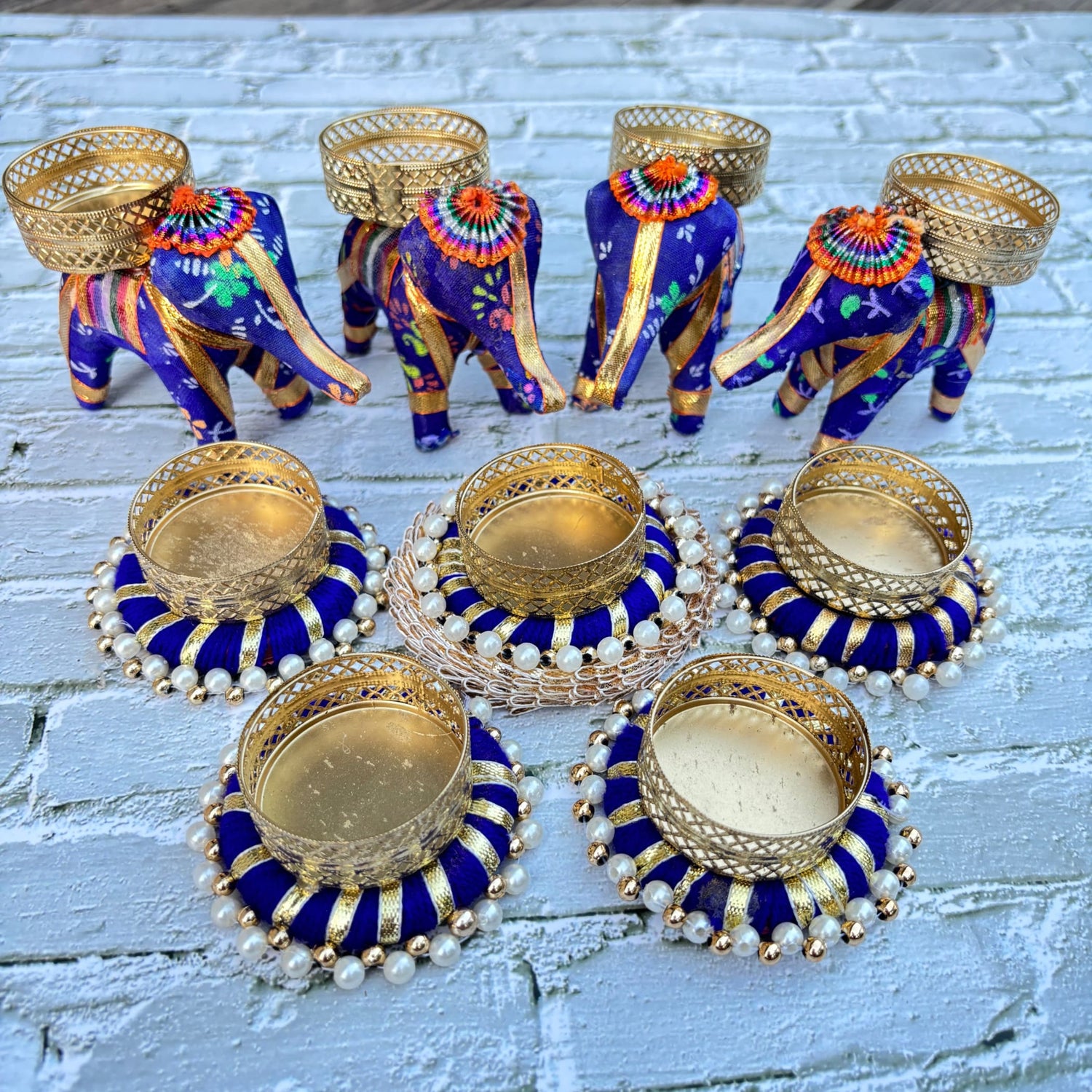 Decorated blue and gold elephant figurines with pearl accents and circular tealight holders