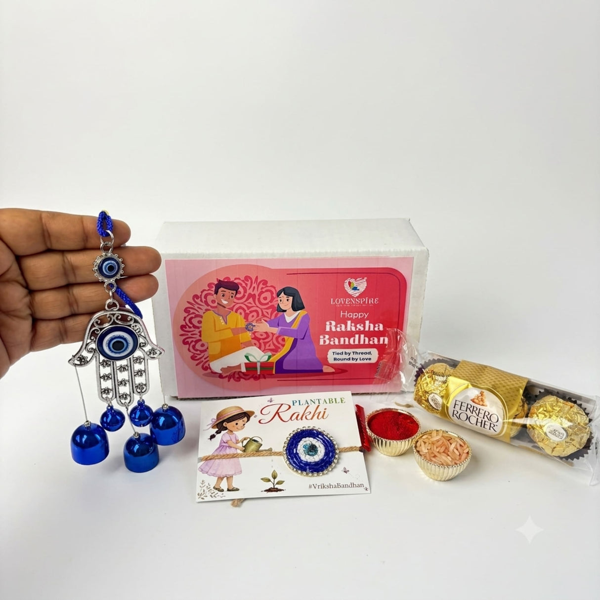 Blue and silver hamsa hand charm with dangling blue bells in evil eye seed rakhi gift hamper for brother