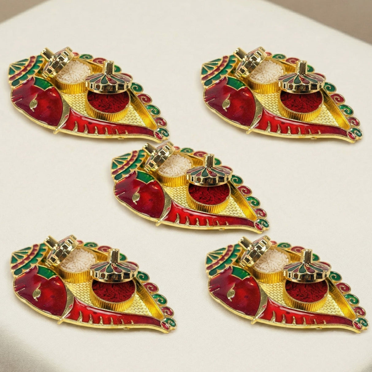 Red and gold enamel diya holders with intricate leaf-shaped designs for indian festival pooja and wedding favors
