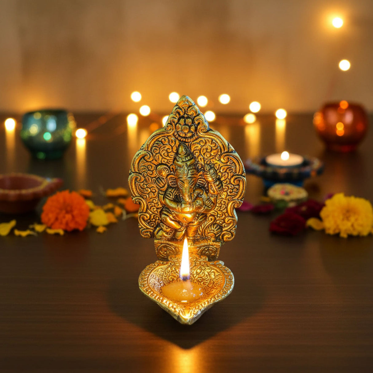 Golden intricately engraved Ganesha brass oil lamp diya with lit candle
