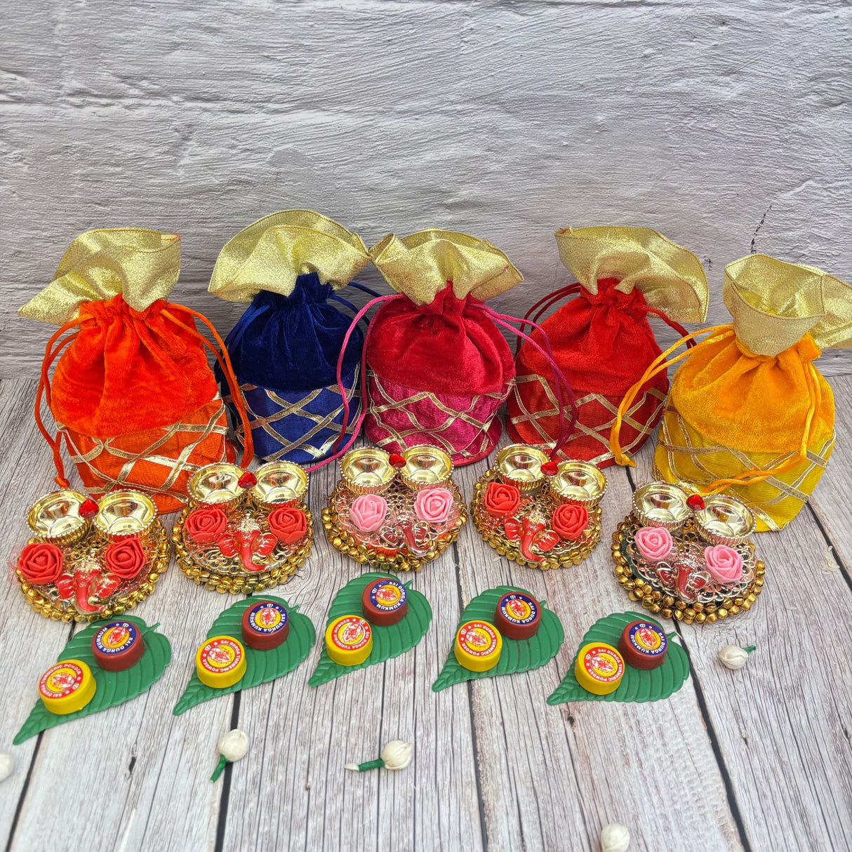 Colorful velvet drawstring pouches with decorative sweets for Ganesha Puja and celebrations
