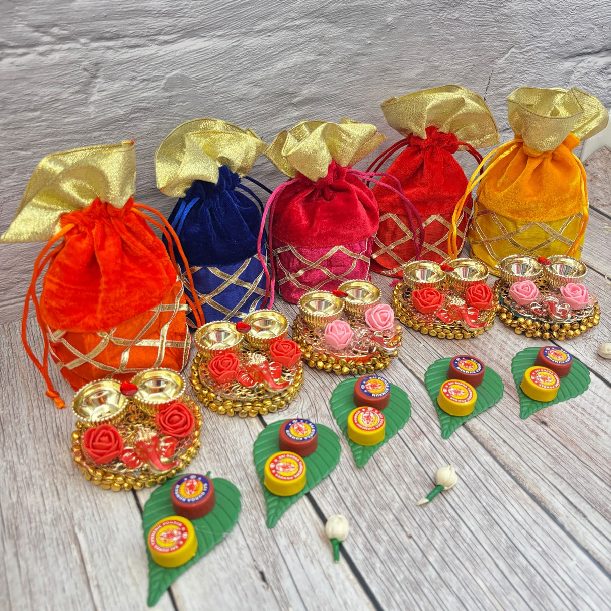 Colorful velvet drawstring pouches with gold accents, decorative trays, sweets, and flowers