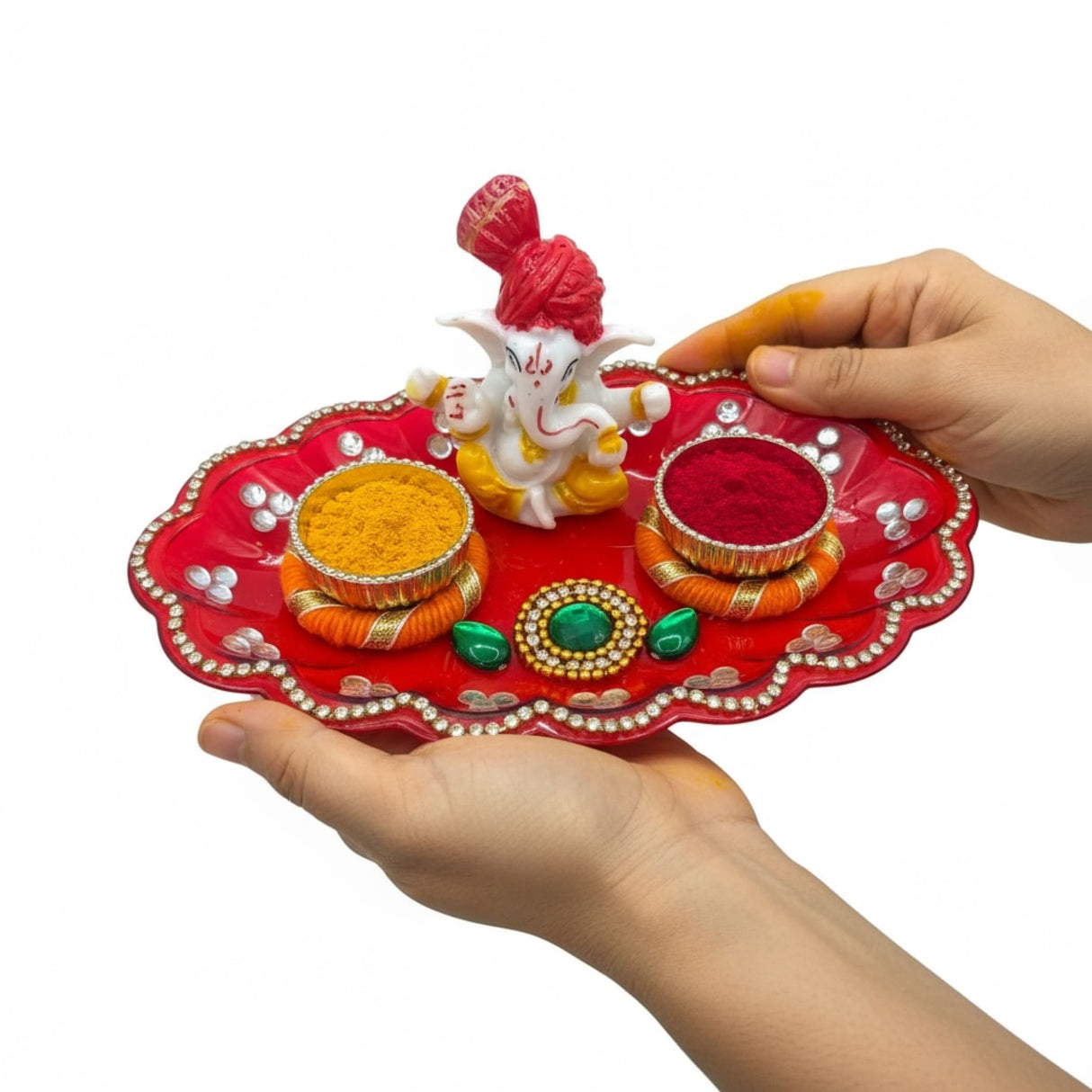 Red and silver decorative tray with intricate designs and a white Ganesha statue for Pooja and Indian celebrations
