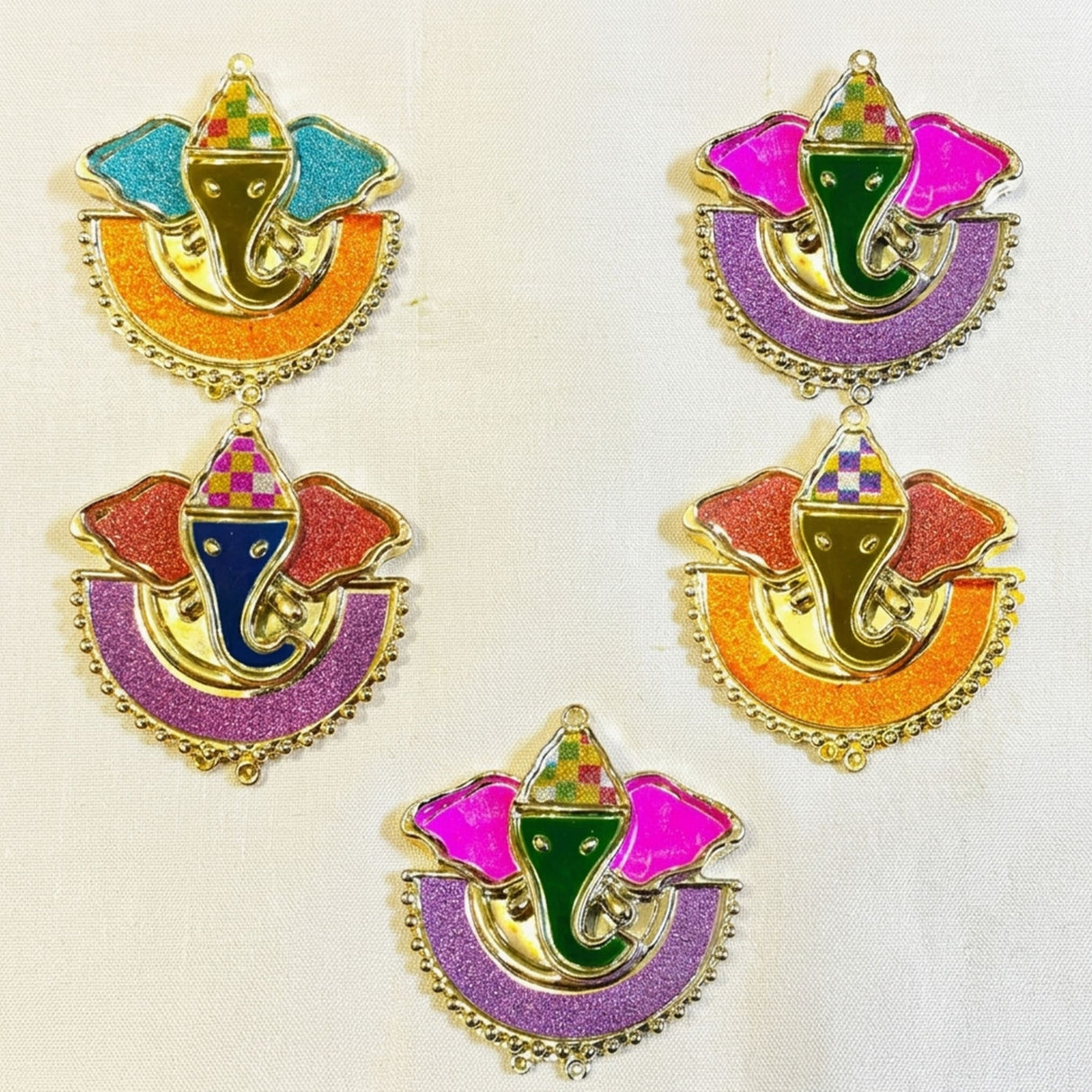 Colorful glittery ganesha shaped haldi kumkum holders with gold metal frames and patterned hats for indian festivals