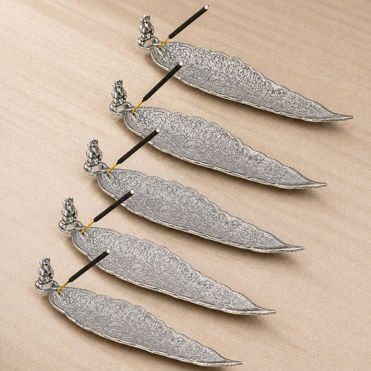Silver leaf-shaped incense holder with intricate filigree patterns and small ganesha figurine stand for home use