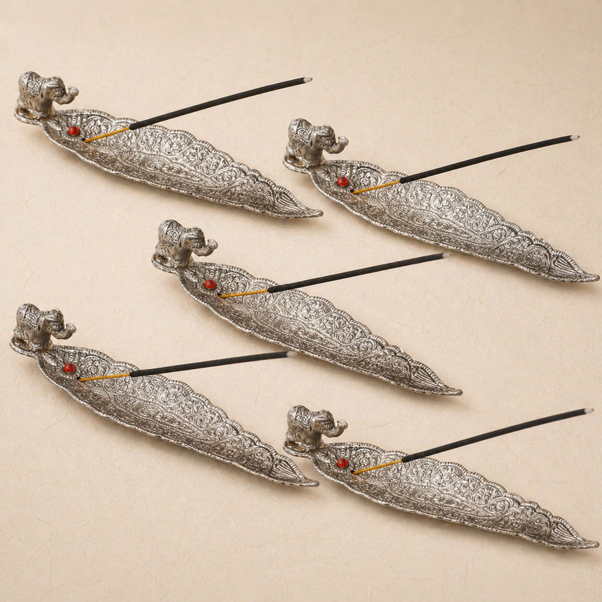 Silver stick incense holder with intricate filigree, elephant figurines, and red gemstone accents for home use