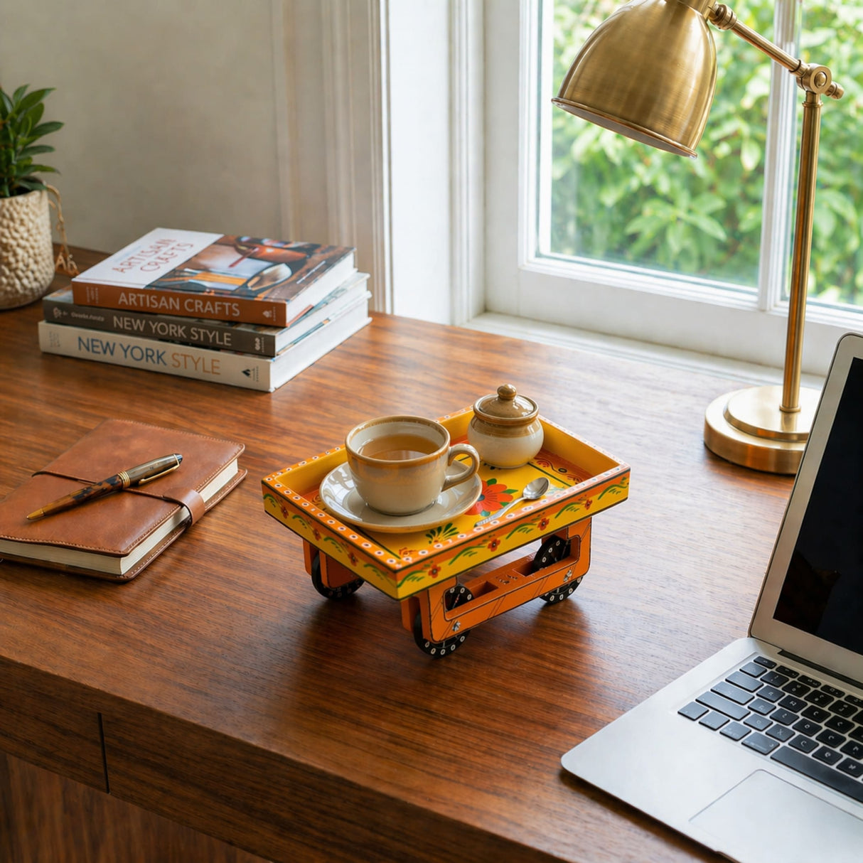 A vibrant orange hand-painted wooden trolley with wheels holding a cup of tea and sugar bowl for serving snacks