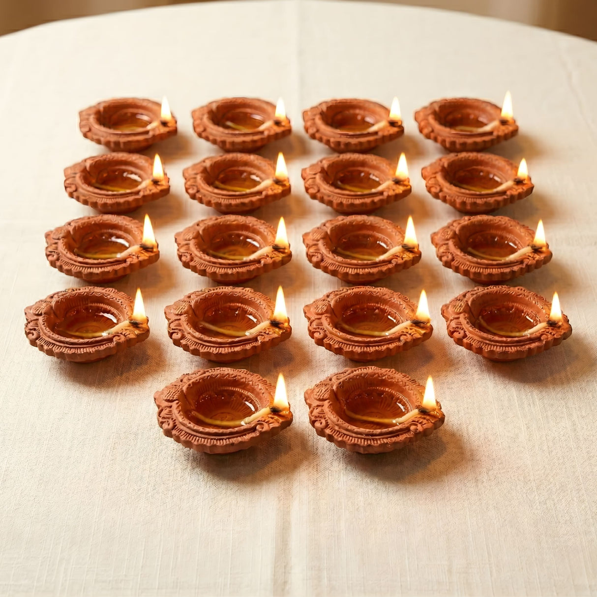 Terracotta clay diya with intricate floral patterns and small flames for diwali pooja and home temple decor